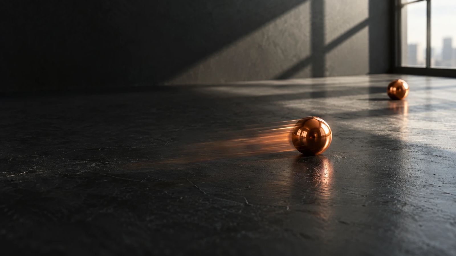 An orange ball bearing rolling across a dark matte surface, a second one at rest behind it